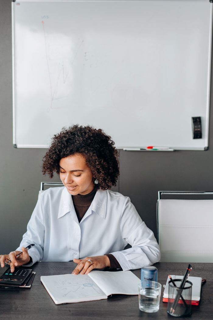 African American woman working with a calculator in an office setting.